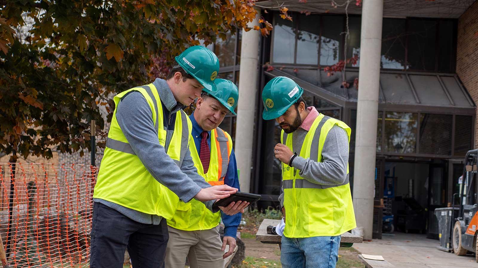 Construction Engineers looking at a tablet on a job site representing 建设 engineering management program at Clarkson university 